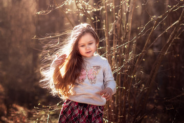  portrait of  beautiful little girl with long hair in the woods on nature