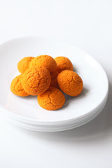 Choux Buns with Craquelin (crispy cream puffs) filled with tropical cream and salted caramel sauce, on white plate, on white background.