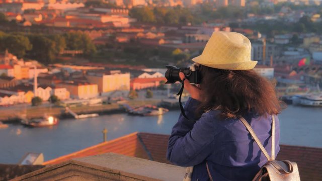 A tourist girl at observation deck takes pictures of view of the Porto city