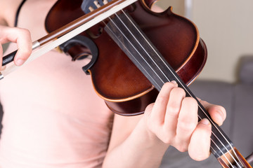 Young woman hand playing classical violin. Teen girl learning to play song