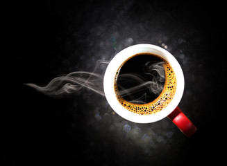 Fragrant black coffee in a cup. Smoke from black hot coffee. Advertising coffee. Glitter lights background. defocused.