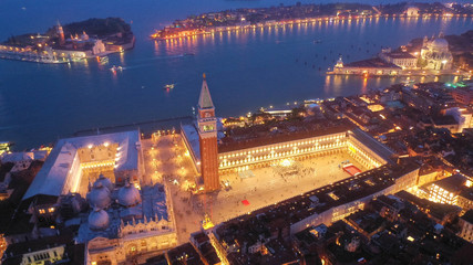 Aerial drone night shot of iconic illuminated Saint Mark's square or Piazza San Marco featuring Doge's Palace, Basilica and Campanile, Venice, Italy