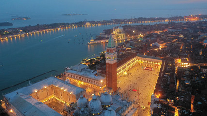 Aerial drone night shot of iconic illuminated Saint Mark's square or Piazza San Marco featuring...