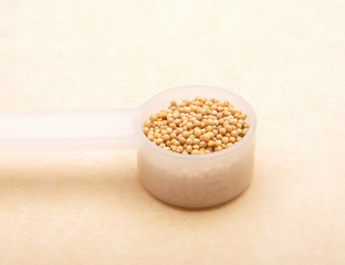 Senfkörner in Dosierlöffel auf braunem Hintergrund