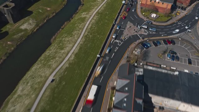 Reverse hyperlapse aerial drone shot of road traffic through town revealing Caerphiilly Castle during busy Spring morning in April with blue skies. Sequenced from DNG raw stills from DJI Mavic 2 Pro