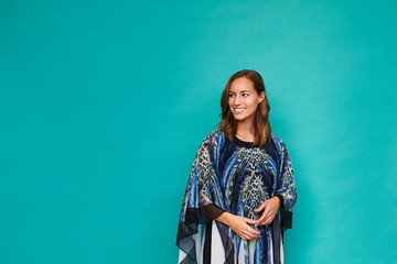 Blue kaftan girl smiling in studio, looking away