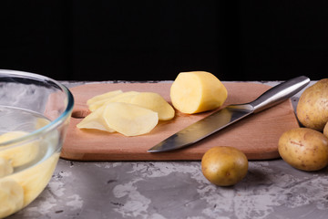 young woman in an apron cuts potatoes
