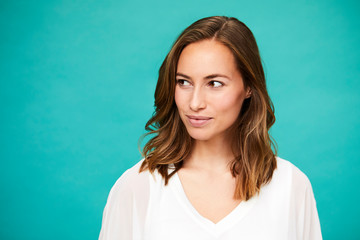 Smiling brunette in blue studio, looking away