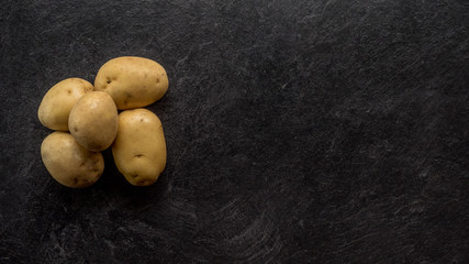 Different cuts of potatoes on a black textured background.