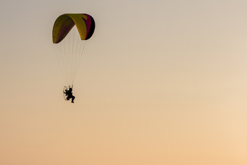 Silhouette of Paramotors flying to sky on sunset Adventure man active extreme sport pilot flying in sky with paramotor engine glider parachute. Paramotor flying on the sky at sunset. 