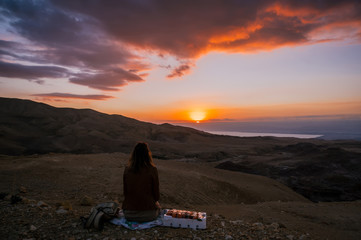 Girl sitting down back sunset view in the desert of Jordan