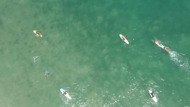 Satelite footage drone, surfers paddling out in the sea. Mancora Beach.