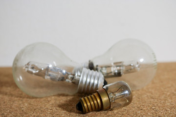 Tre lampadine appoggiate su un fondo di sughero con lo sfondo bianco