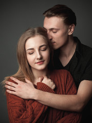 Cheerful couple hugging on the gray background.