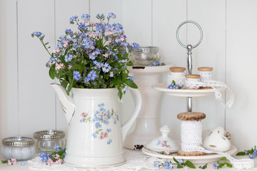 Dekoration mit Vergissmeinnicht-Blumenstrauß in vintage Teekanne