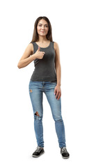 Fototapeta premium Young beautiful smiling woman in gray sleeveless top and blue jeans standing and givng thumbs-up isolated on white background.