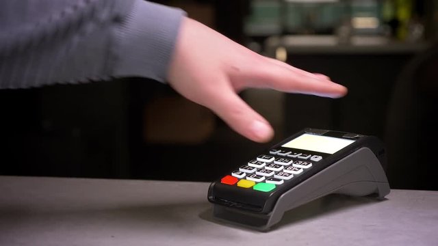 Close-up shot of man attaches hand with microchip implant to terminal making successful contactless payment.