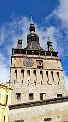 Fototapeta na wymiar Sighisoara clock tower is the main entry point to the citadel, opposite guarded by Taylor's Tower. With its 64 meters of height, the tower is visible from almost every corner of the city