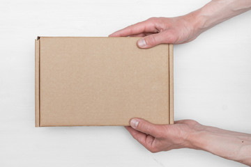 A parcel cardboard box in a delivery man hands on a white wooden table background. Delivery service...
