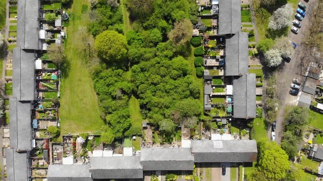 Aerial view slowly moving to the left over a residential area comprising of mid terrace houses with woodlands at the rear in Basildon on a sunny day