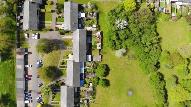 Top down flying over a residential area comprising of mid terrace houses with woodlands at the rear in Basildon on a sunny day