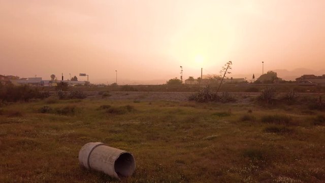 Tubo in amianto cancerogeno e velenoso abbandonato su un terreno con cielo avvolto dalla tempesta di sabbia. Concetto di inquinamento industriale.