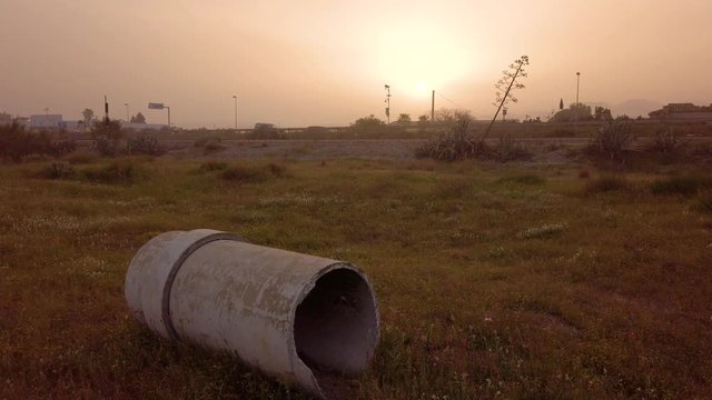Tubo in amianto cancerogeno e velenoso abbandonato su un terreno con cielo avvolto dalla tempesta di sabbia. Concetto di inquinamento industriale.