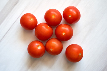 Small cherry tomatoes on a light wooden background