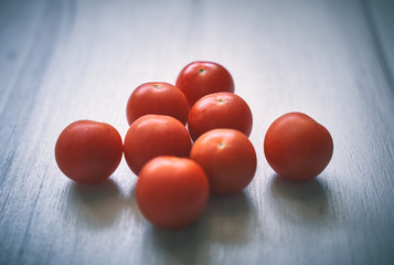 Fototapeta na wymiar Small cherry tomatoes on a light wooden background