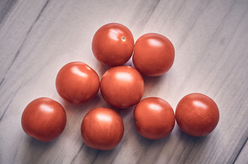 Small cherry tomatoes on a light wooden background