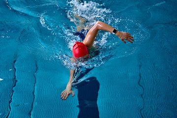 Female athlete swimming fast in crawl style.  Splashes of water scatter in different directions.