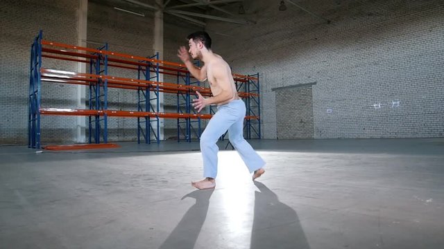 An acrobatic man training his skills. Showing capoeira elements. Performing an air kick