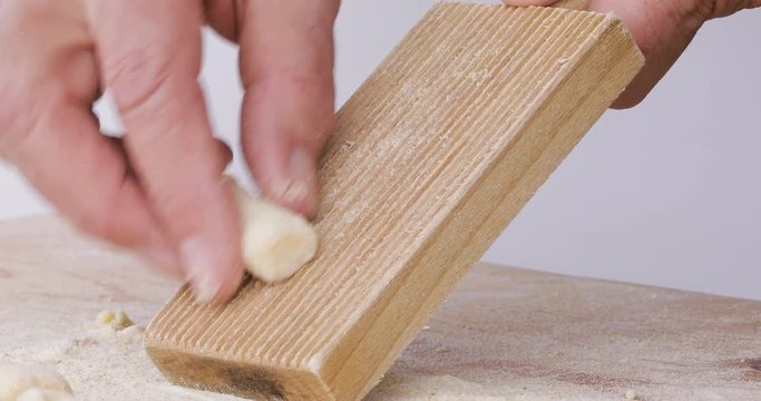 Mani di un uomo che fanno la preparazione degli gnocchi di patate fatti in casa con rigagnocchi e tagliere in legno.