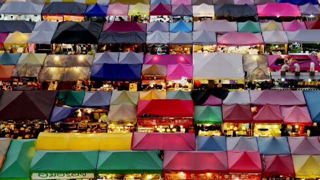Night market called train night market Ratchada bird eye view, people visit to enjoy many kind of street food, located at back of Esplanade Ratchadapisek Department store, Bangkok, Thailand, tilt up.