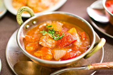 bowl with typical indian food, spicy chicken in tomato soup, garlic, parsley