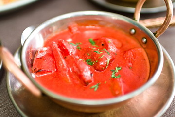 bowl with typical indian food, spicy chicken in tomato soup, garlic, parsley