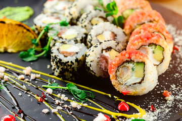 Beautiful looking sushi, sushi as work of art. Closeup sushi rolls top view, rice, cavair, flower garnish and wasabi.