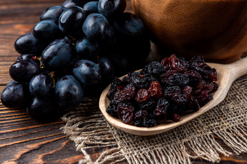 Raisin and grapes on dark wooden background.