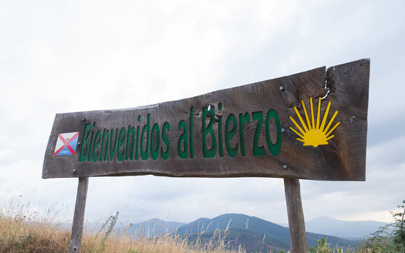 Letrero indicador de madera, con la inscripci&oacute;n " Bienvenidos al Bierzo" que anuncia la entrada en  El Bierzo con la bandera de la comarca y el s&iacute;mbolo del Camino de Santiago