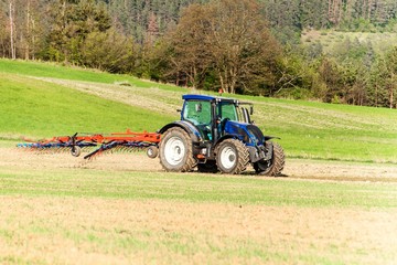 Blue tractor in the field. Working on an agricultural farm in the Czech Republic. Spring work in agriculture.
