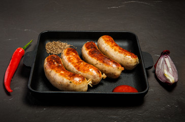 square pan with sausages, ketchup, caraway, chili, and onion
