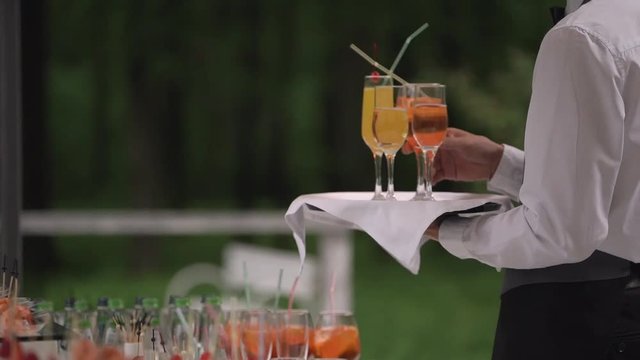 waiter puts the glasses of drinks on the tray that would take them to guests. catering