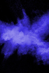 Abstract blue dust explosion on black background. Freeze motion of blue particles splashing. Painted Holi in festival.