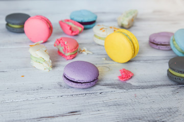 Colorful macaron cakes on the white wooden background. White, yellow, pink, purple and grey french macarons with fresh berries.