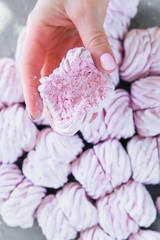 Woman's hands holds freshly prepared homemade marshmallow against a background of a lot ofmarshmallows. Natural marshmallows