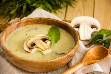 Mushroom soup with champignons. Paleo diet, chicken broth soup with mushrooms and cheese. Soup in a wooden bowl with a wooden spoon. Background about lunch. Copy space