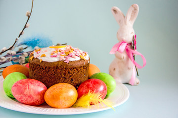 Easter cupcake, Easter bunny statute and painted Easter eggs on a plate, near willow twigs. Easter background, copy space