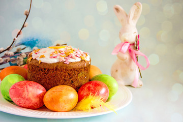 Easter cupcake, Easter bunny statute and painted Easter eggs on a plate, near willow twigs. Easter background, copy space