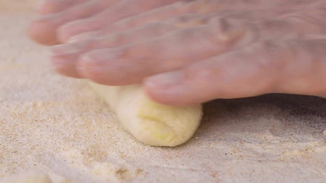 Mani di un uomo stanno preparando e impastando gli gnocchi di patate. Con farina integrale e uova fatti in in casa, su un tagliere di legno.