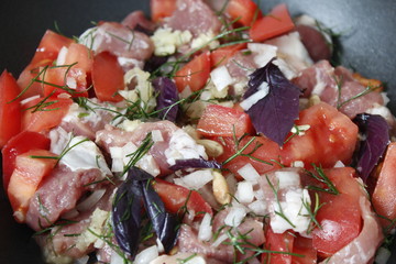 Pan with raw beef, tomatoes, dill, garlic, onion, basil, lemon juice